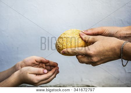 Hands Of A Child Take A Bun From The Hands Of An Adult. Peace. Sadness