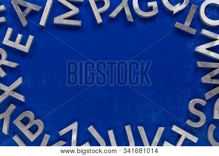 Frame Mockup Made Of Of Silver Metal English Alphabet Characters On Blue Background.