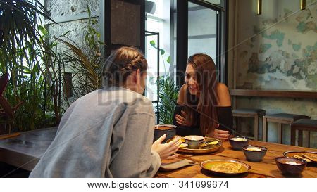 Two Girls At Lunch, They Sit And Talk To Each Other Wispering