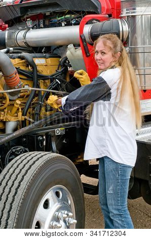 Woman Truck Driver Checking The Oil Level On A Big Truck