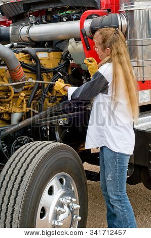 Woman Truck Driver Checking The Oil Level On A Big Truck