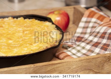 Shephers Pie Baked In A Cast Iron Skillet And Placed On A Wood Tray With An Apple And Napkins