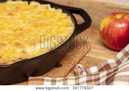 Shephers Pie Baked In A Cast Iron Skillet And Placed On A Wood Tray With An Apple And Napkins