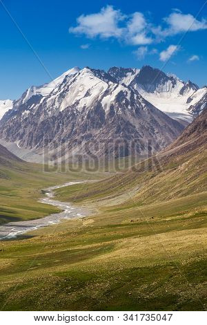 Majestic Snow Capped Mountains Or Glacier Landscape With Green Alpine Meadows And Stream Running In 