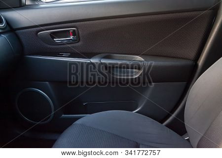 The Interior Of The Car With A View Of The Passengers Door With Buttons, Armrest And Black Upholster