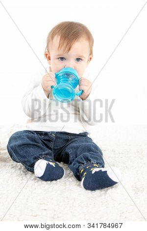 Stock Studio Photo With A White Background Of A Baby Drinking Water From A Canteen With Handles.