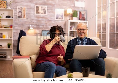 Elderly Old Couple Using Modern Laptop To Chat With Their Grandson