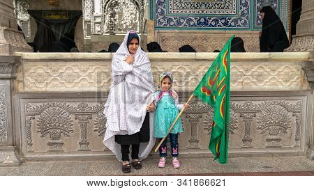 Shrine Of Fatima Masumeh, Qom, Iran - May 2019: Iranian Women And Her Daughter Holding An Islamic Ba