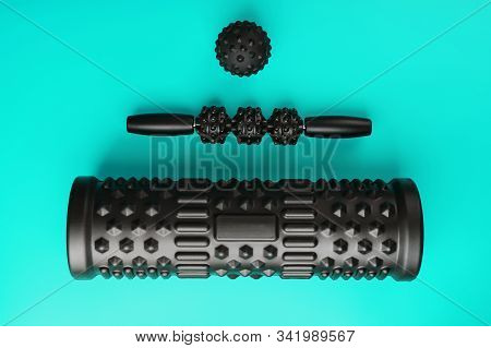 A Set Of Black Bumpy Foam Massage Rollers, Body Rollers, Rubber Balls On A Blue Background.