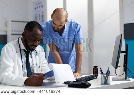 African American Therapist Doctor Analyzing Medicine Documents Discussing Healthcare Treatment With 
