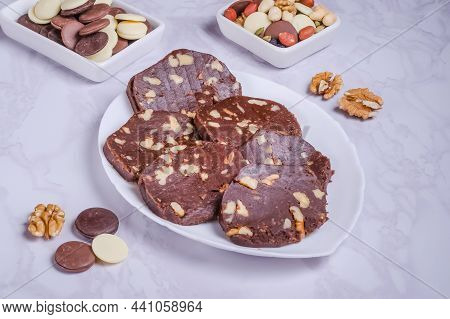 Dessert Chocolate Sausage With Nuts On A White Plate On A Marble Background