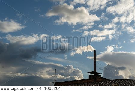 Chimney Of An Industrial Ceramic Factory Where Black Smoke Comes Out, In A Blua Sky With Clouds. Cli