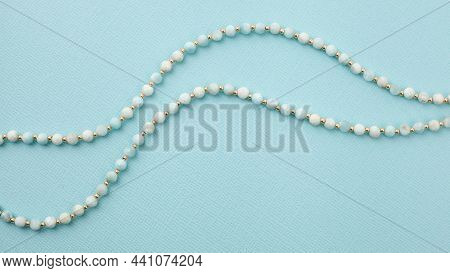 Two Wavy Lines Of White Gem Stones On Bright Textured Turquoise Background. Top 
View