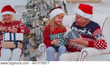 Granddaughter Exhcanging Christmas Gift Present Boxes With Lovely Happy Senior Grandfather At Home. 