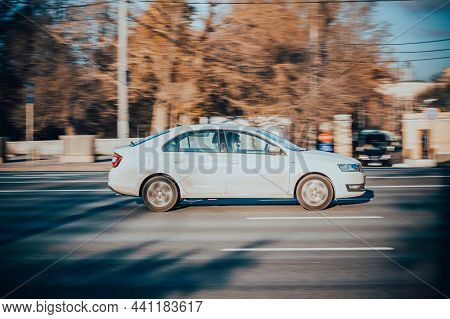 White Skoda Rapid Small Family Car Moving On City Road. Driver With Passenger In 4-door Sedan Rushes