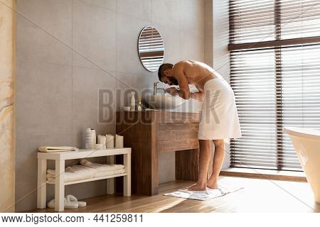 Portrait Of Man Washing His Face At Bathroom