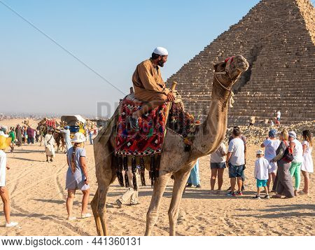 Giza, Cairo, Egypt - September 30, 2021: Egyptian In National Dress Sits Astride A Camel. Tourists W