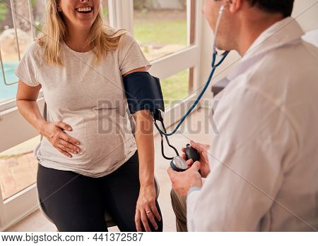 Caucasian Female Mother To Be Sitting With Doctor Measuring Blood Pressure