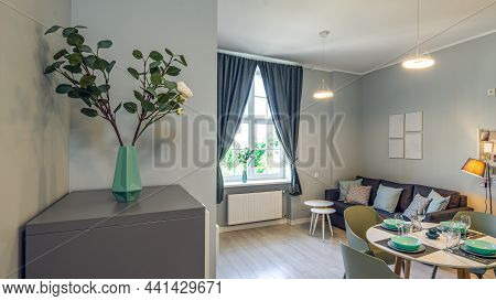 Modern Interior Of Studio Apartment In Grey Colors. Living Room With Cozy Couch. Dinner Table Is Set