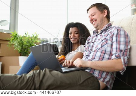 Portrait Of Friends Sitting On Carpet Floor Watching Movie On Laptop And Laughing. Latino American W