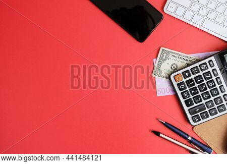 Creative Flat Lay Of Workspace Desk With Laptop, Caculator And Notebook On Red Colour Background. Bu
