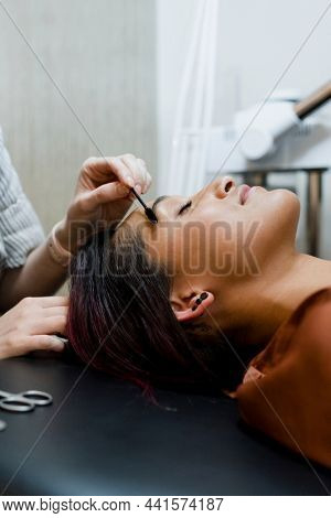 Beautician giving eyebrow treatment to a customer at a beauty salon