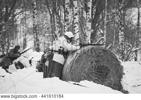 Re-enactor Dressed Like German Wehrmacht Infantry Soldier In World War Ii Aiming Rifle From Hay Roll