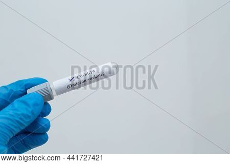 Hand Holding Tube Which Has Text Written As Covid - 19 (omicron Variant) On With Isolated White Back