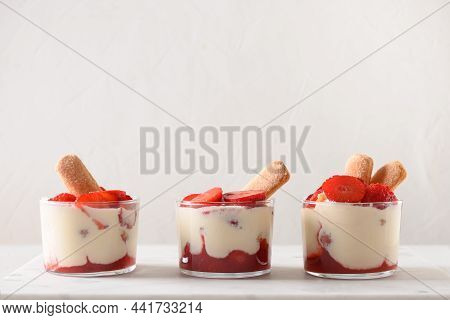 Three Portion Of Layered Dessert In Glass Jars With Cookie Savoyardi, Mascarpone Cheese And Whipped 