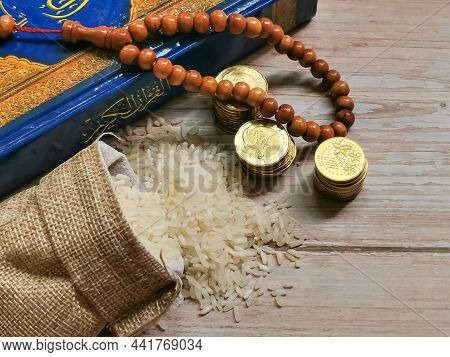 Zakat Concept. Selective Focus Rice In Sack With Coins,rosary And Koran. Zakat Is A Mandatory Proces