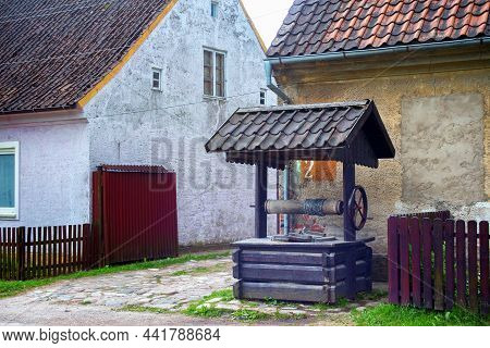 Krasnolesye, Russia - June 12, 2016: View Of The Wooden Well And The Old Historical German Buildings