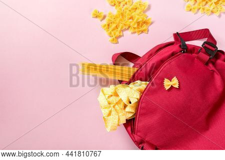 A Red Backpack With Various Pasta On A Pink Background. Food Delivery Concept, Shopping, Farm Shoppi