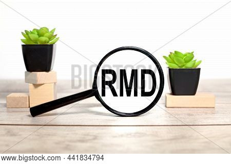 Rmd. Text In A Black Magnifying Glass On A White Background On A Wooden Table And Plants In A Pot