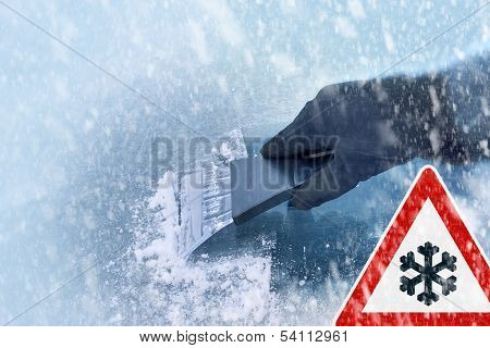 winter driving - scraping ice from a windshield