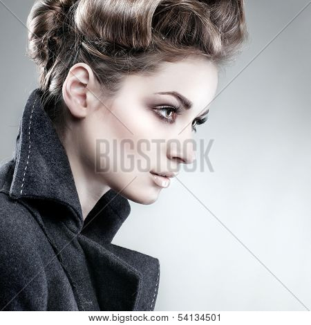 Portrait of elegant young woman in a grey overcoat  on a grey background