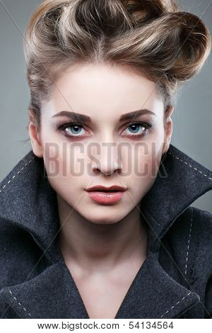 Portrait of elegant young woman in a grey overcoat  on a grey background