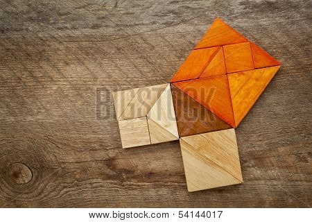 Pythagorean theorem illustrated with wooden pieces of tangram, a classic Chinese puzzle, against barn wood background