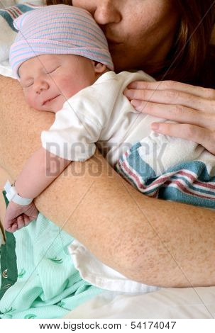 Mother Kissing Smiling Newborn Baby