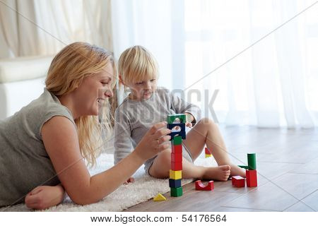Mother with a child playing with wooden blocks at home