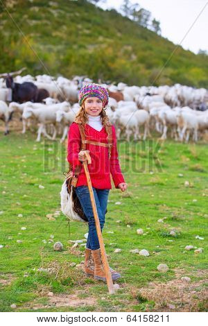 Kid girl shepherdess happy with flock of sheep and wooden stick in Spain
