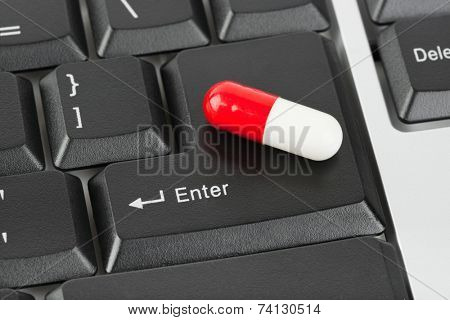 Pill on computer keyboard - concept technology background