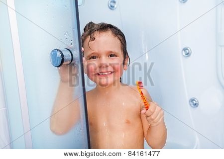 Happy boy with toothbrush showering in the cabin