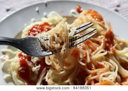 Spaghetti with ketchup and cheese on a plate.