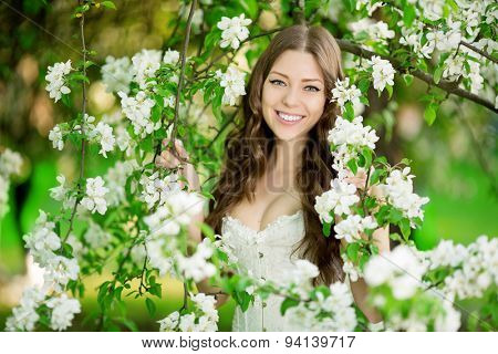 Young spring fashion woman in spring garden Springtime Summertime Trendy girl in the flowering trees in then at sunset in spring summer landscape background Allergic to pollen of flowers Allergy 