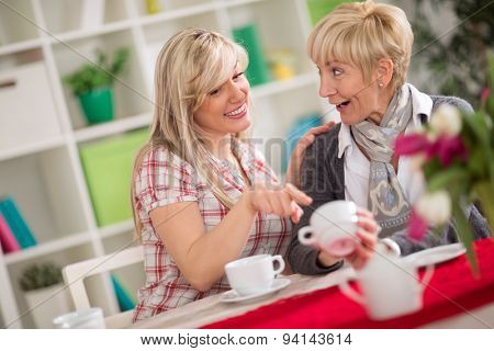 two females talking and drinking coffee, younger woman augury looking at cup of coffee