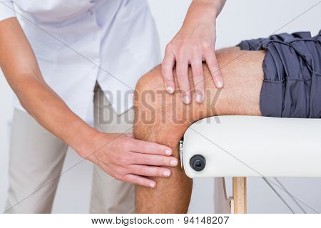 Doctor examining her patient knee in medical office