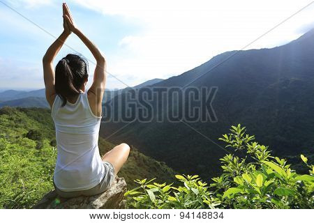 young yoga woman sit meditation on mountain peak rock