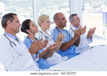 Team of doctors applauding during meeting in medical office
