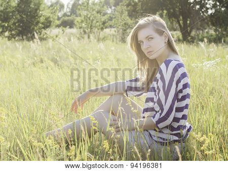 beautiful young woman sitting on hay.