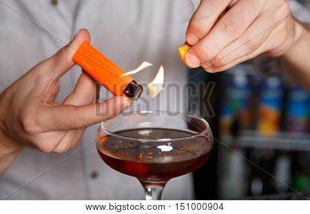 Barman's hands in bar interior making alcohol flaming cocktail. Professional bartender at work in bar mixing drink with burning fire. Party time in night club
